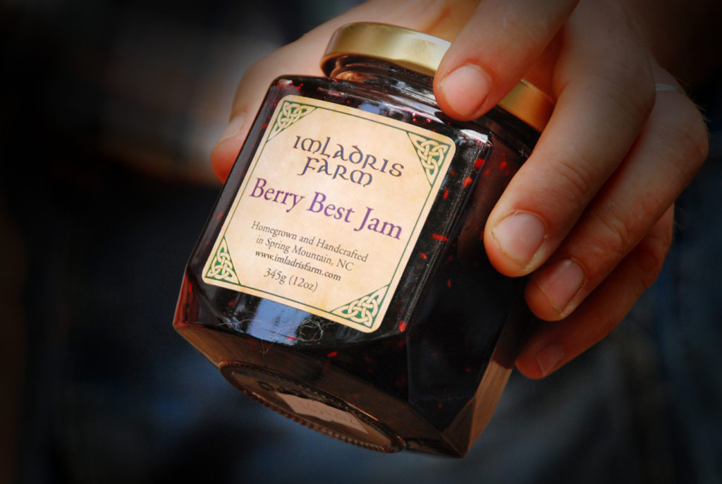 A person holding a jar of Imladris Farm Berry Best Jam.